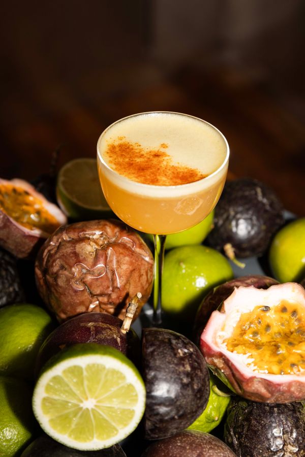 Crimes of Passion cocktail surrounded by passionfruit and lime