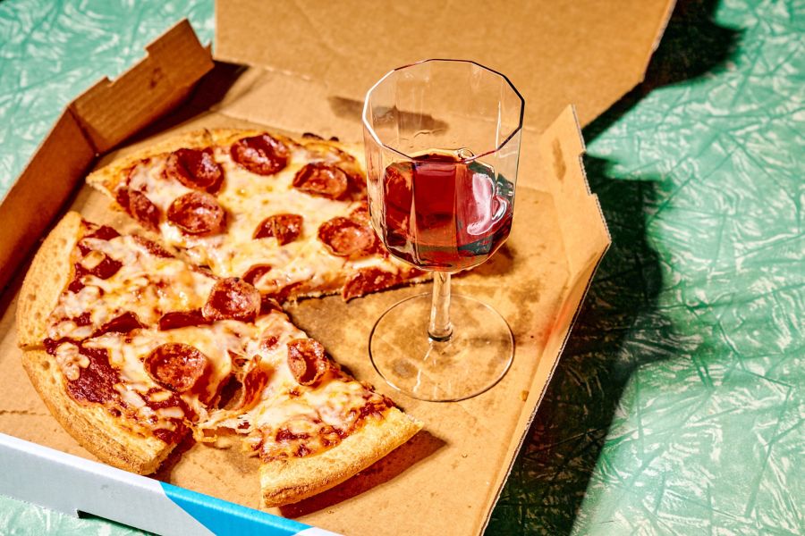 Pepperoni pizza in a box with a glass of nebbiolo