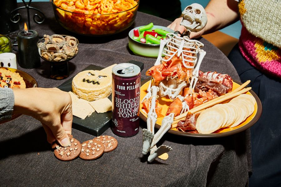 Can of Four Pillars Bloody Shiraz Gin & Tonic on table with Halloween-themed snacks