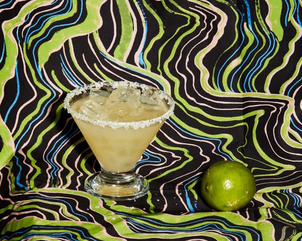 A salt-rimmed cocktail with a lime