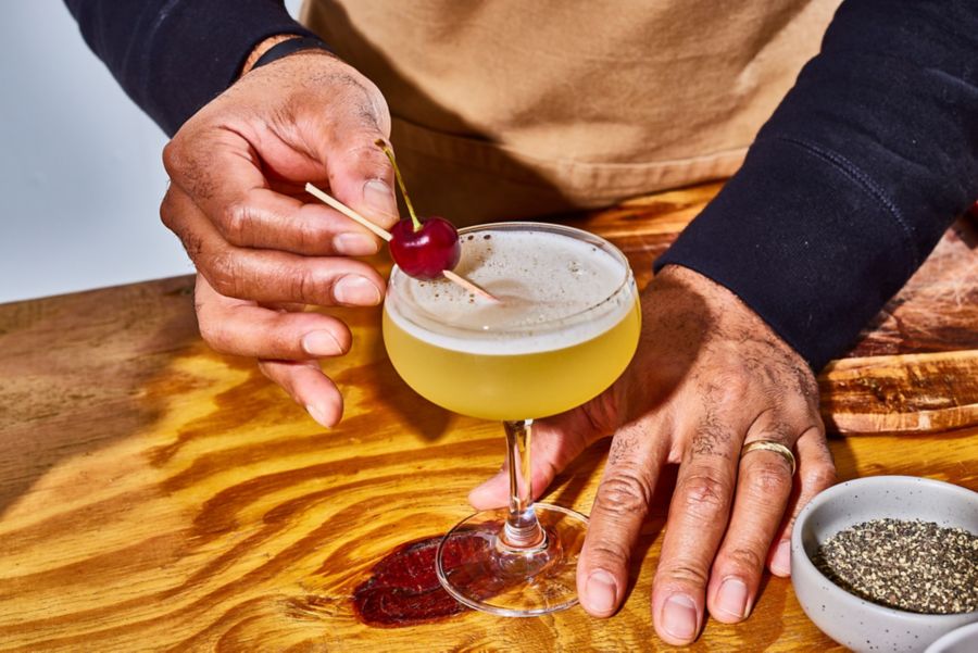 Garnishing a cocktail with a skewered cherry