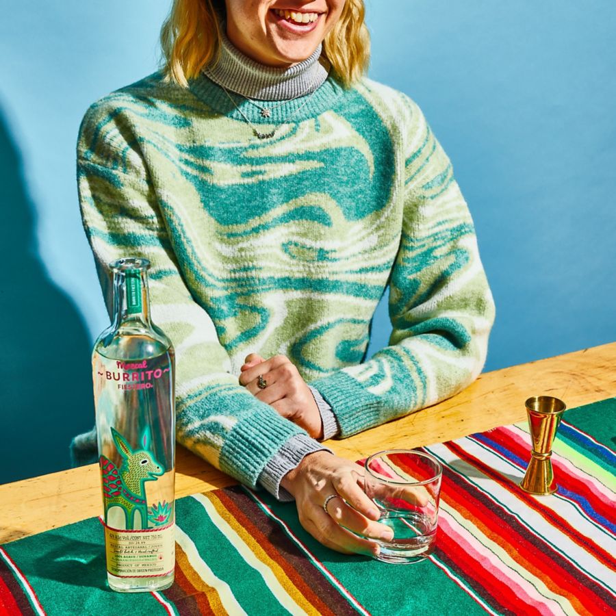 Holding a glass of the Burrito Festero Mezcal 