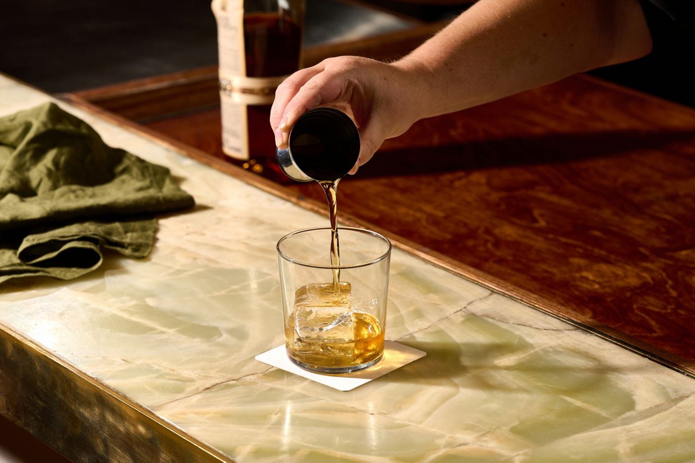 Pouring whisky into a glass over ice