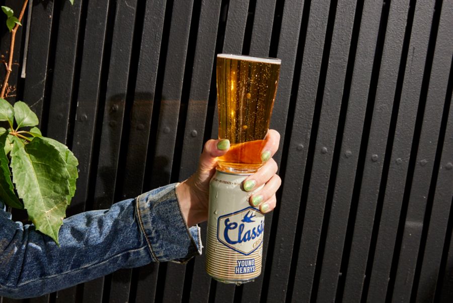 Holding a glass and a can of Young Henrys Classic Crisp Mid