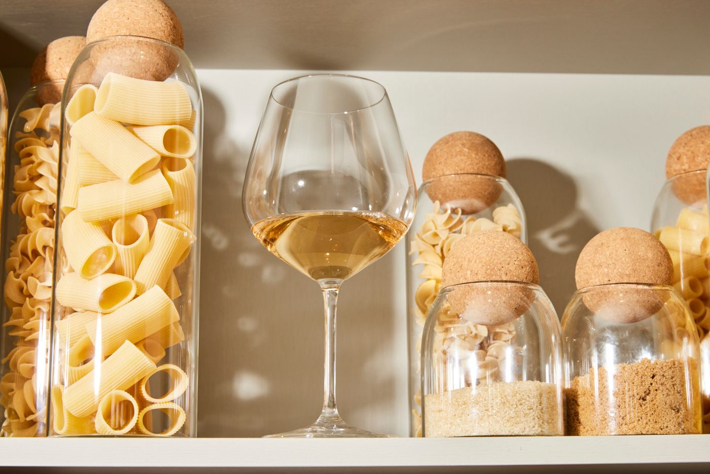 A glass of white wine on a pantry shelf