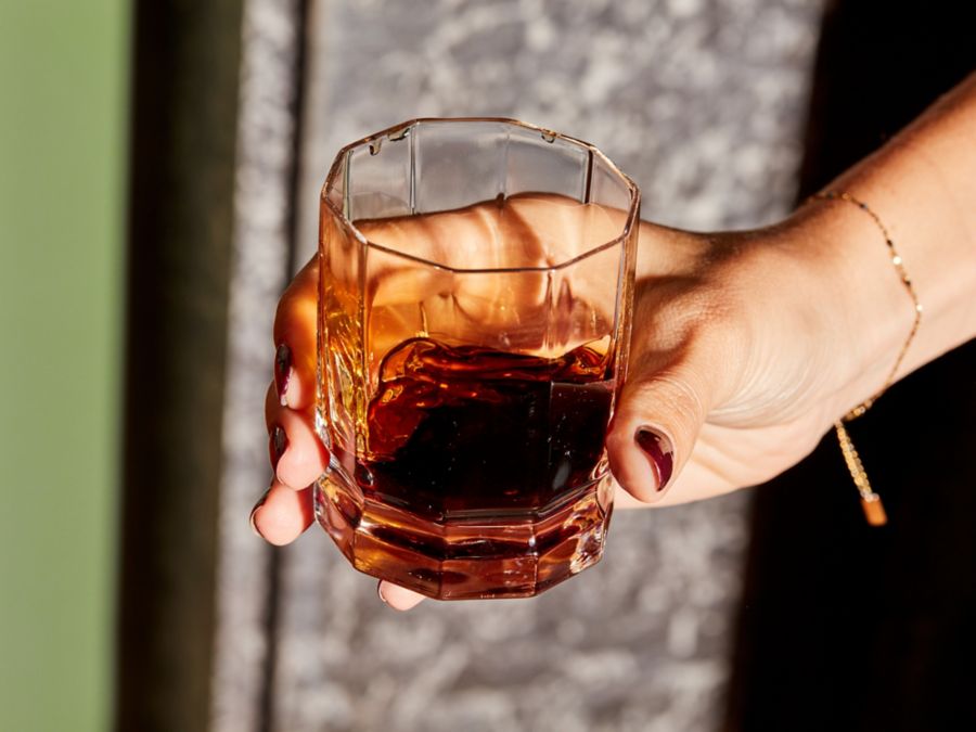 Holding a glass of the bittersweet liqueur amaro