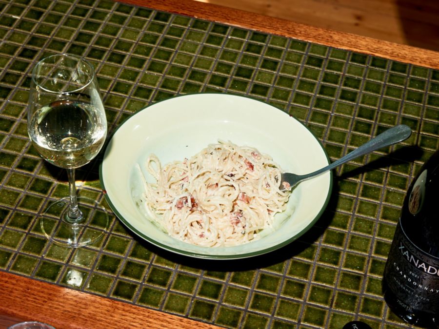 A bowl of creamy pasta with a glass of chardonnay 