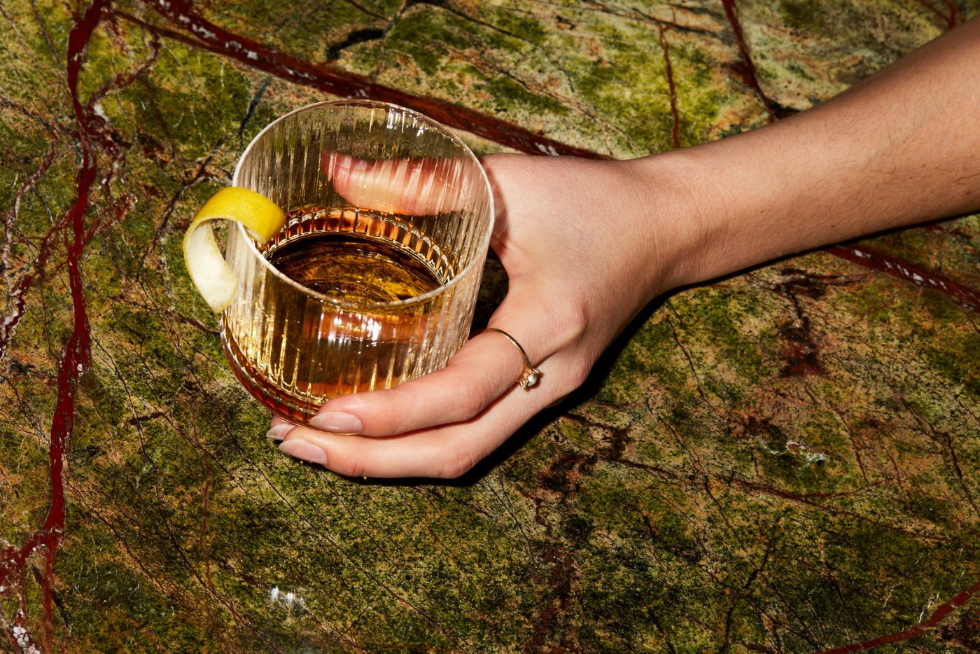 Holding a Bacon Washed Old Fashioned cocktail that's ideal for winter