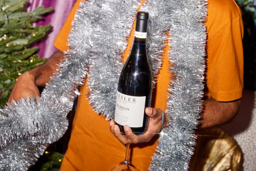 Holding a bottle of Kaesler The Bogan with Christmas tinsel 