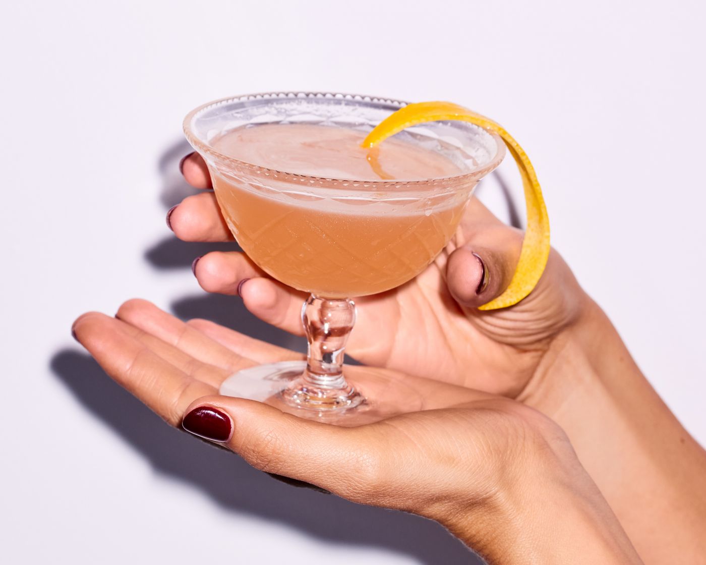 Holding a short coupe glass holding the Army and Navy cocktail 