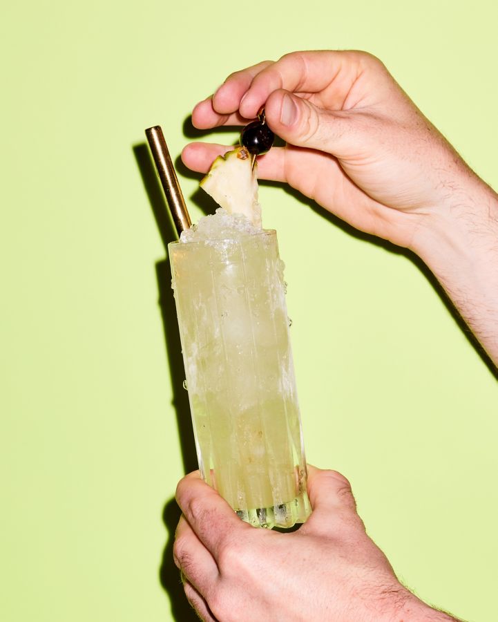Holding a glass of the Chartreuse Swizzle