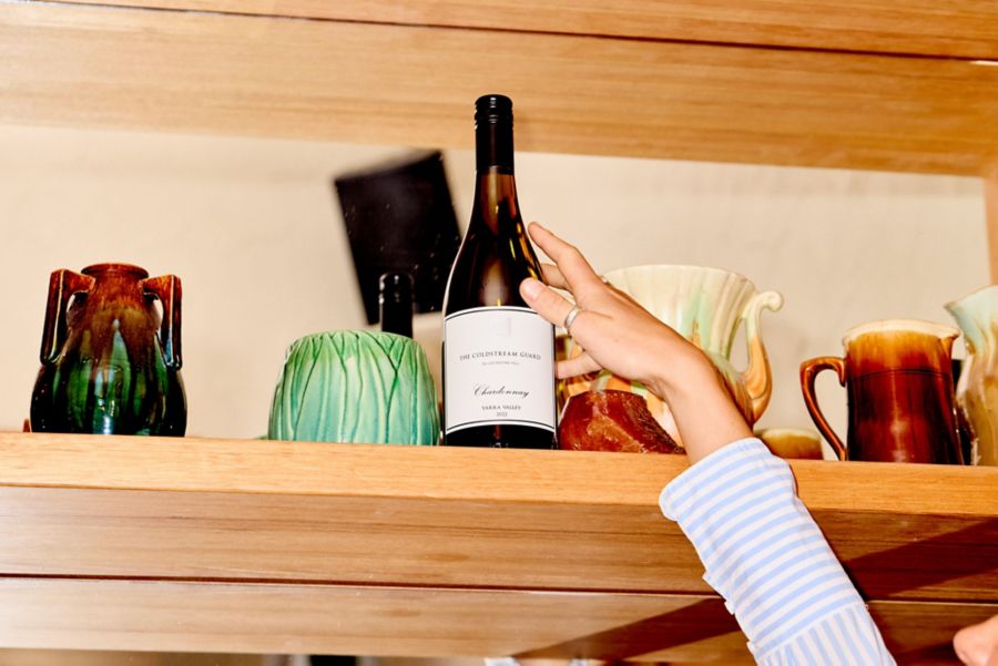 Reaching for a bottle of Coldstream Guard Chardonnay on a shelf