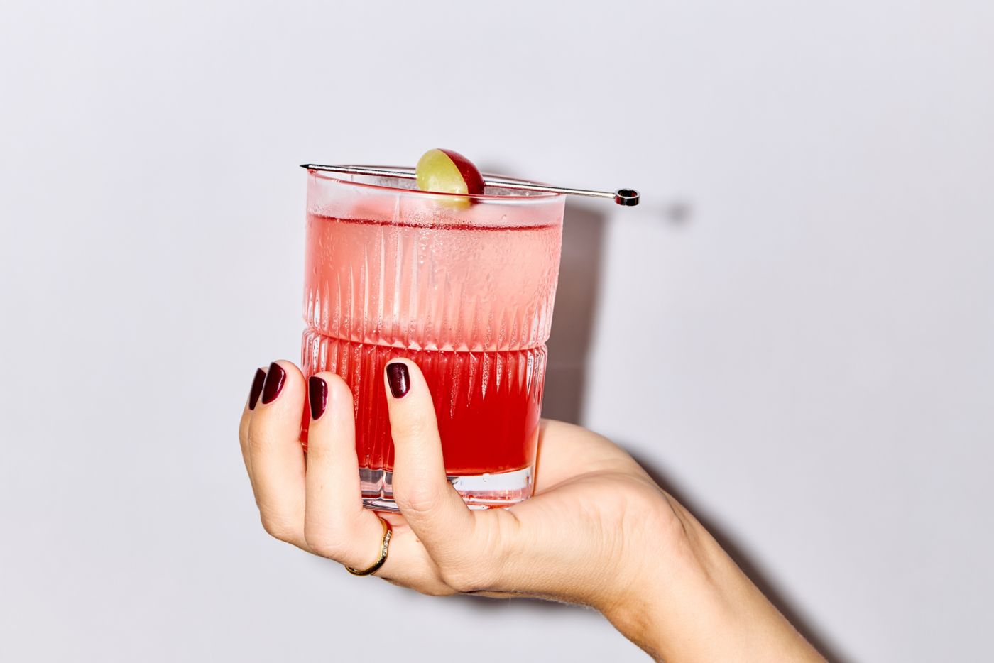 Holding the Enzoni cocktail, which includes muddled grapes in the recipe