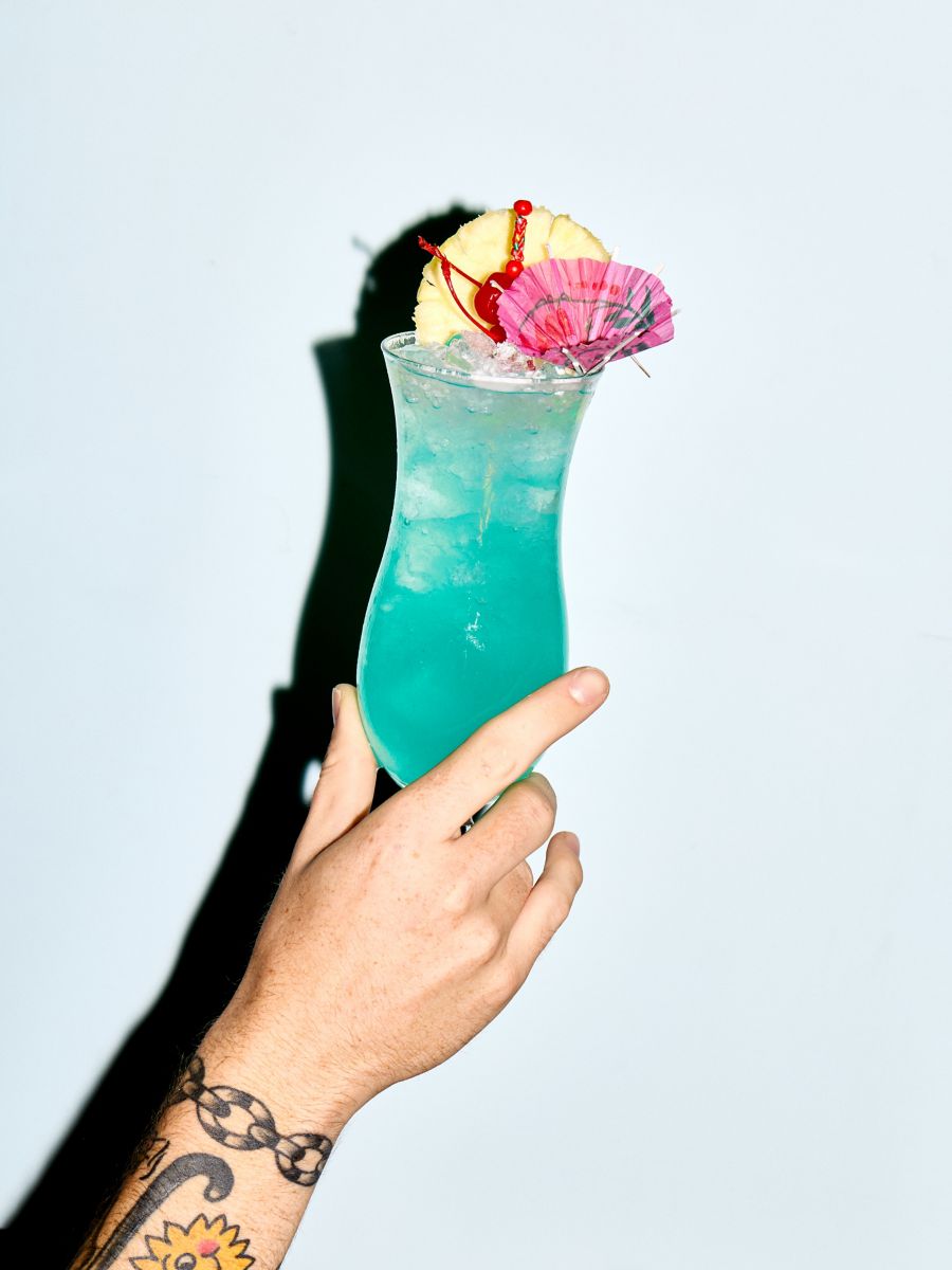 Holding a Blue Hawaii cocktail in a hurricane glass