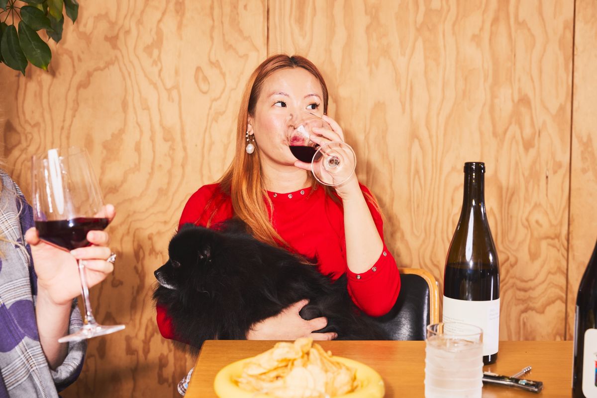Christine Lafian sipping on red wine while holding her dog