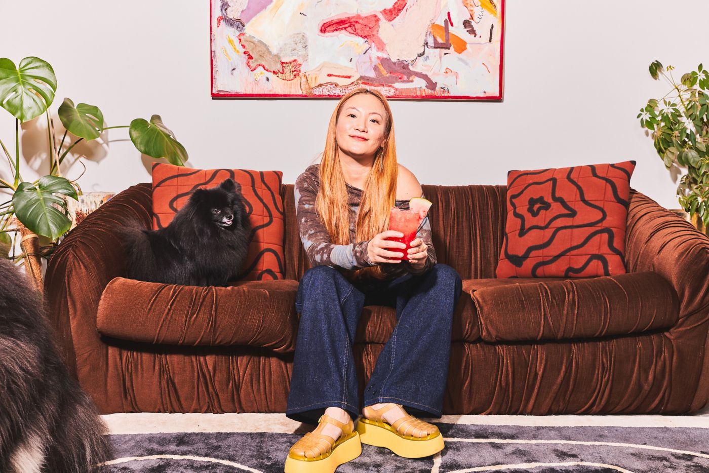 Christine Lafian of SUKU Home with her dog on a brown sofa.  