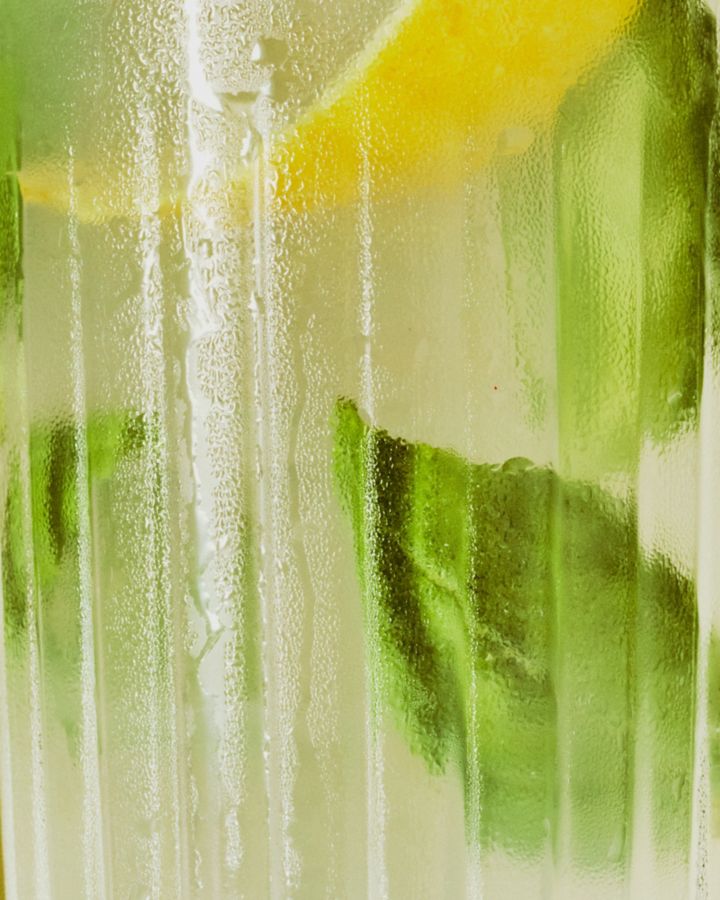 A close-up shot of the Amalfitano cocktail, with lemon peel & basil leaves