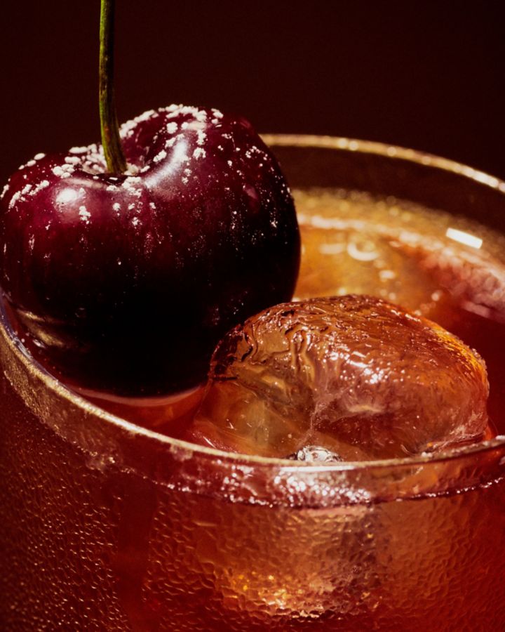 Bourbon Cherry Cola with a cherry dusted with icing sugar as garnish