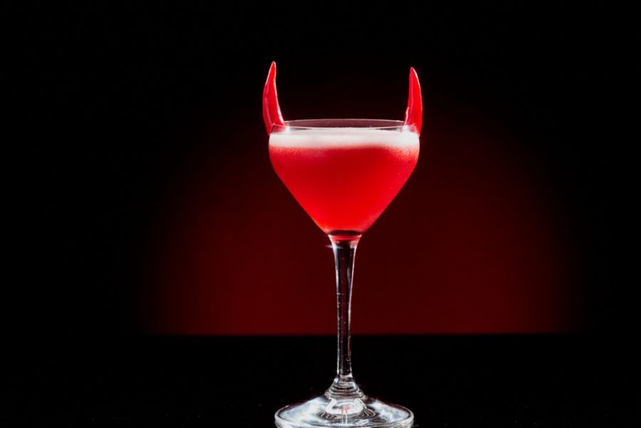 Holding the Devil's Horn cocktail, which is perfect for Halloween 