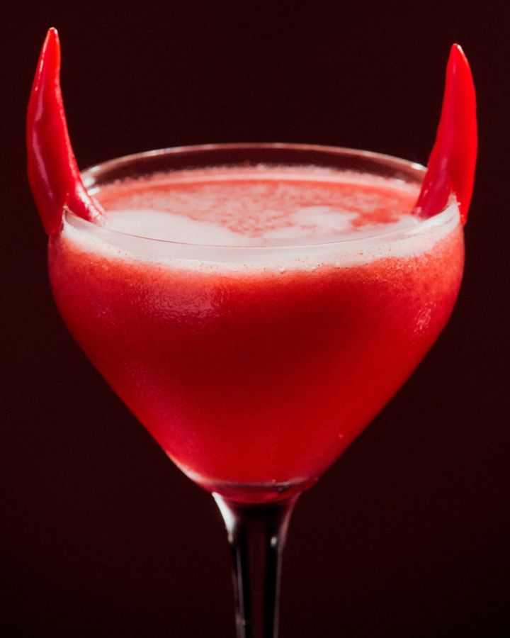 A close-up shot of the Devil's Horn cocktail, with chillis as garnish on the rim of the glass