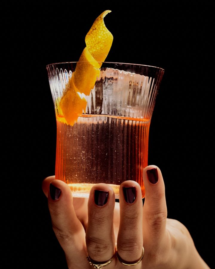 Holding a Clarified Paper Plane cocktail with a lemon peel
