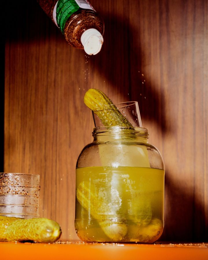 A Spicy Pickle Margarita cocktail on top of a jar of pickles
