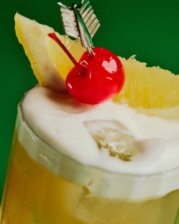 Up close on an Amaretto Sour, garnished with lemon and a cherry 