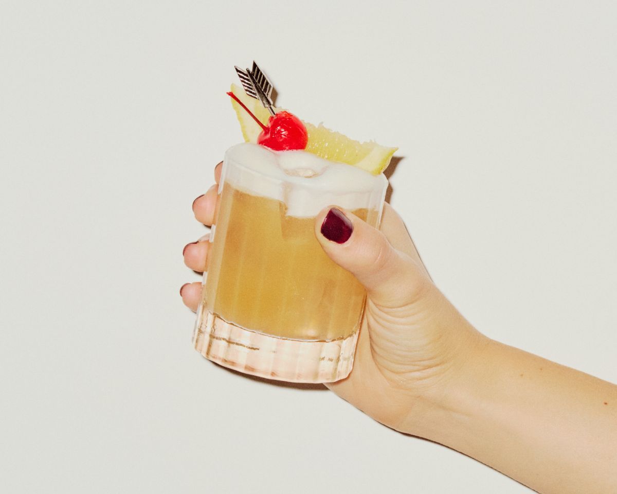 Holding an Amaretto Sour cocktail