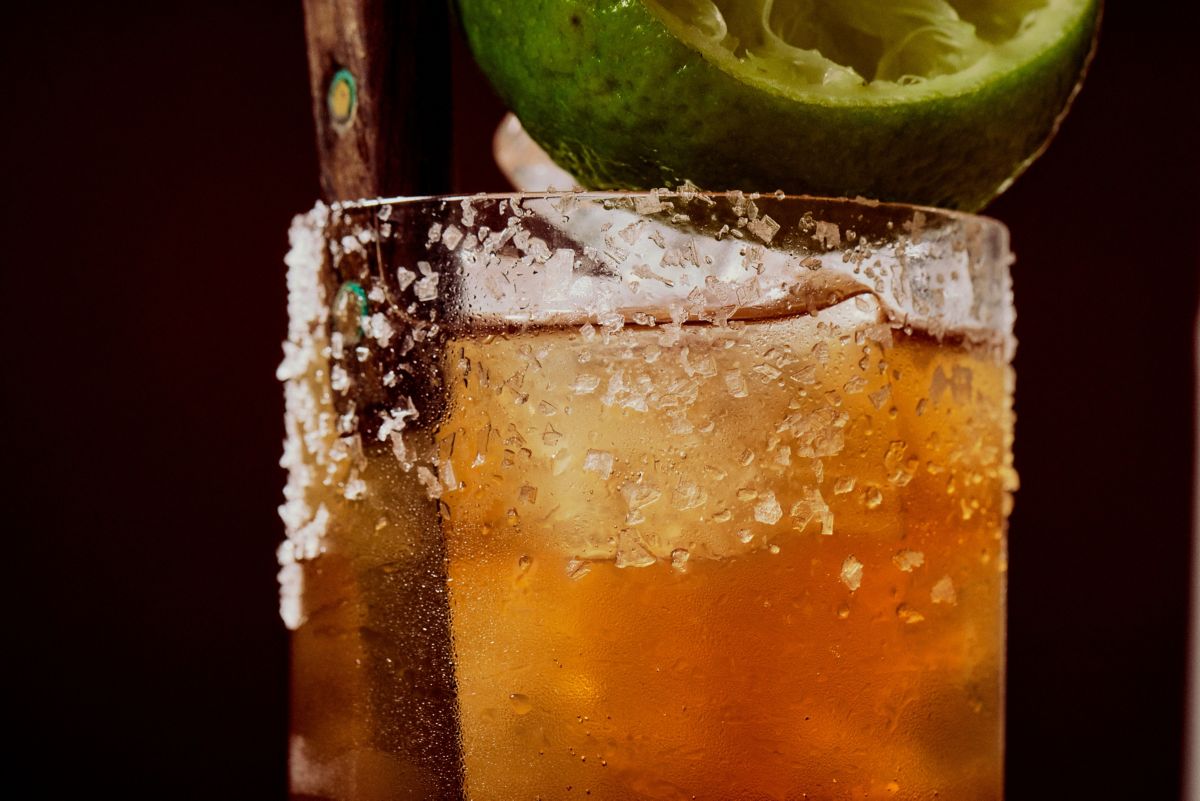 Close-up of Batanga cocktail garnished with lime wedge and salt flakes on rim