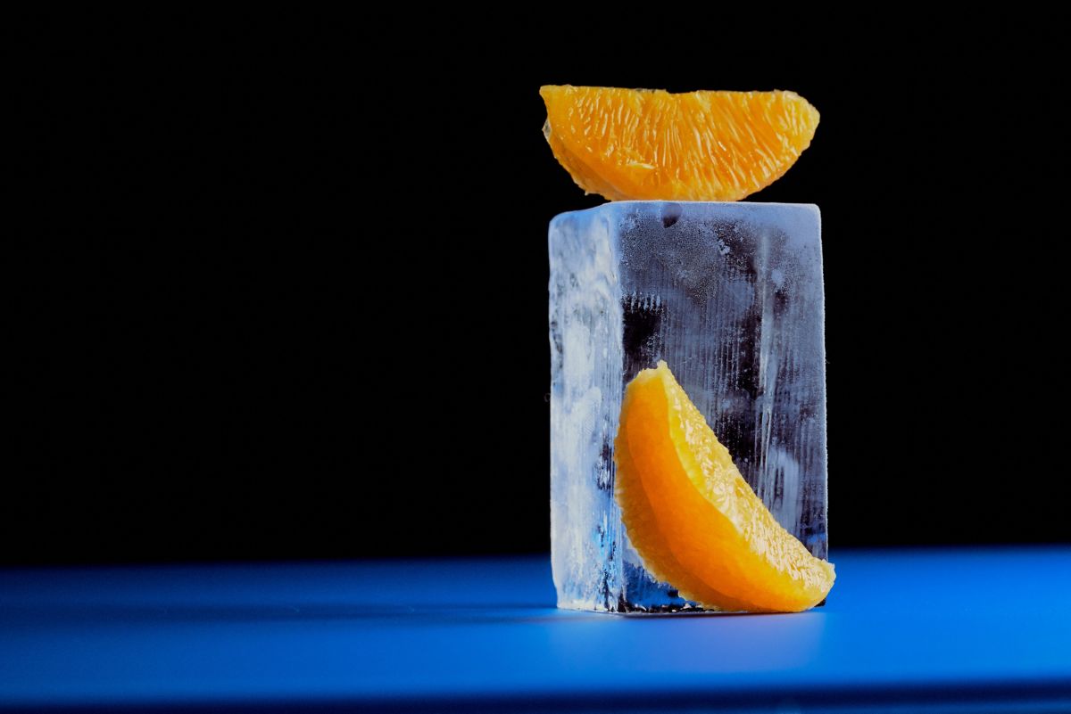 A large ice cube and segments of orange to go into the Bicicletta cocktail 