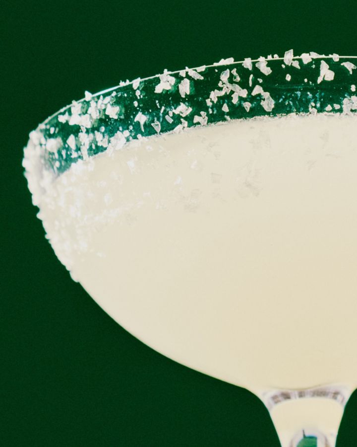 Holding a Margarita cocktail, with a salt rim