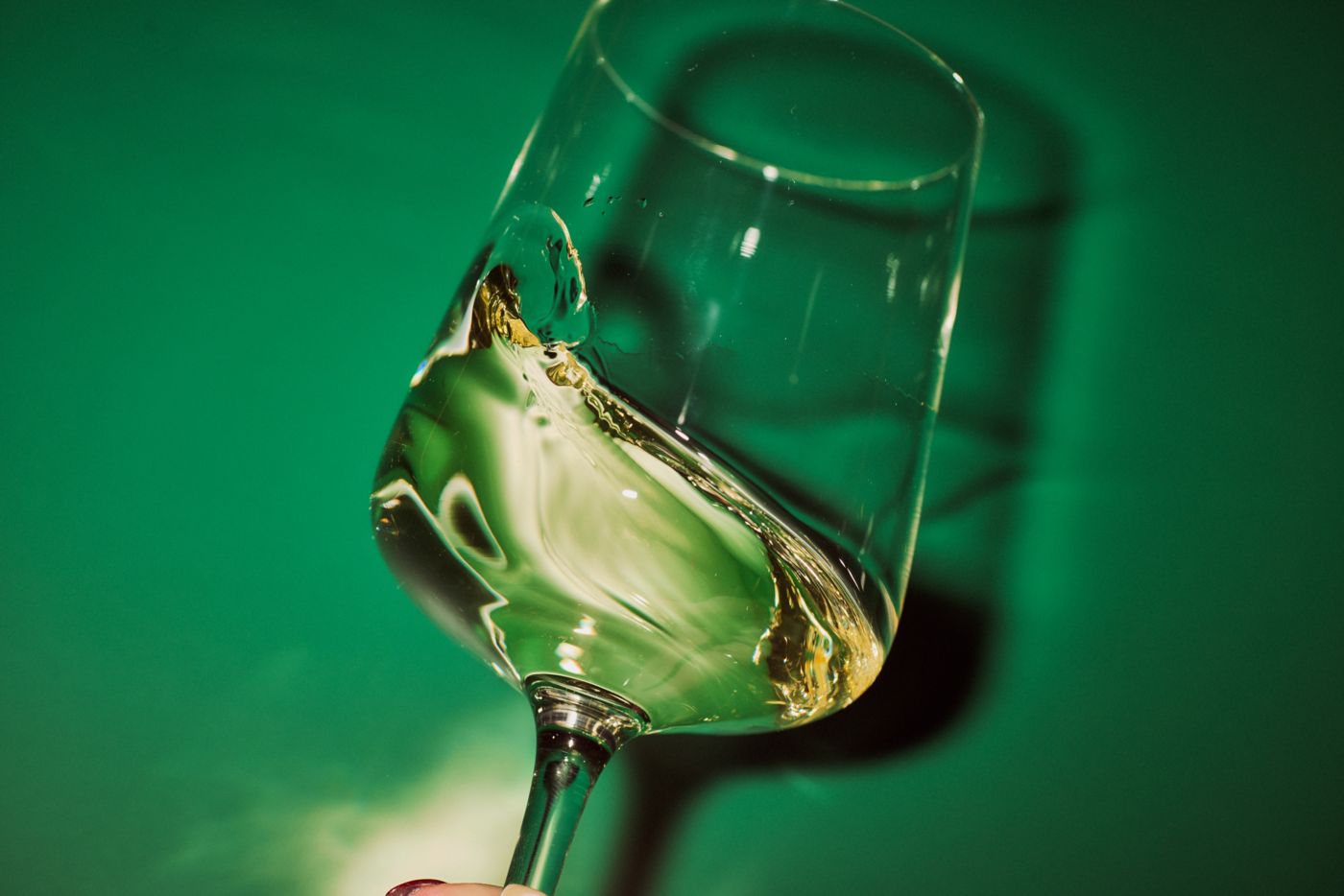 Swirling a glass of white wine against a green background