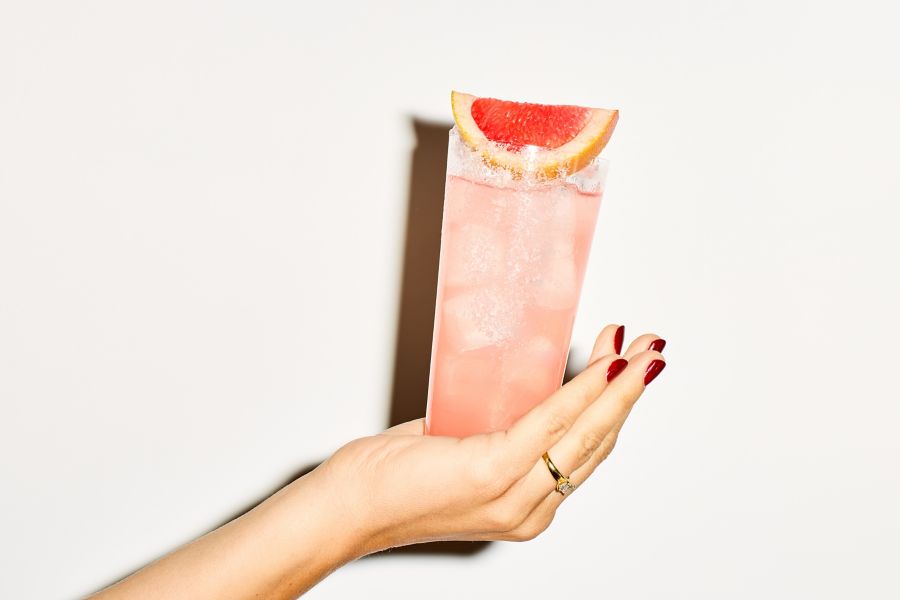 Holding a Paloma, garnished with a wedge of grapefruit on top