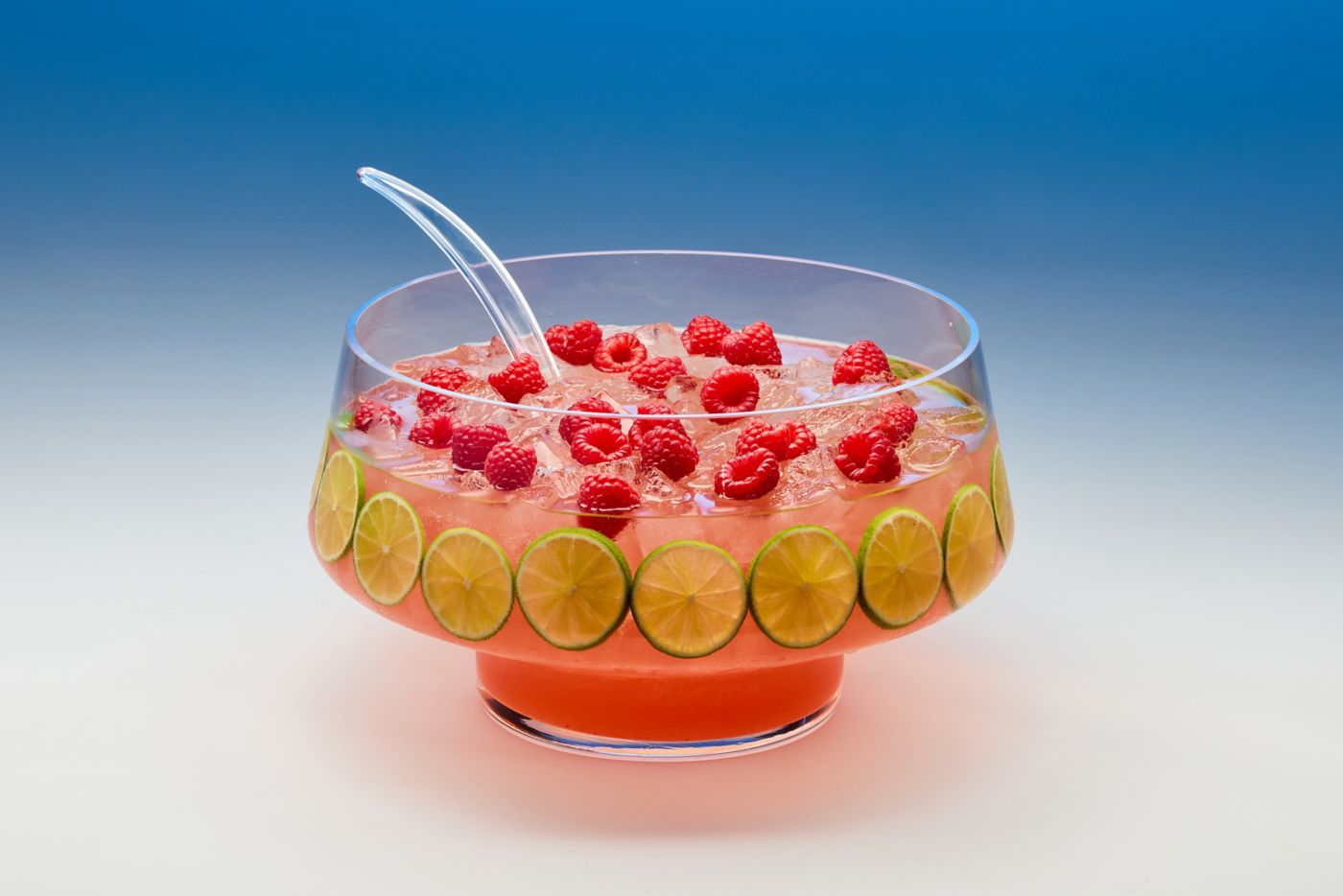 A punch bowl of Raspberry Tequila Sangria, garnished with lime wheels and raspberries 