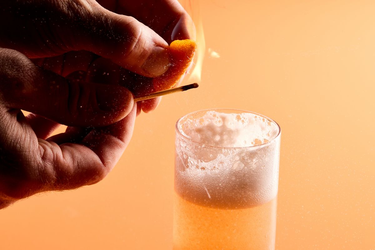 Flaming the orange peel garnish over the Cosmo Bellini 