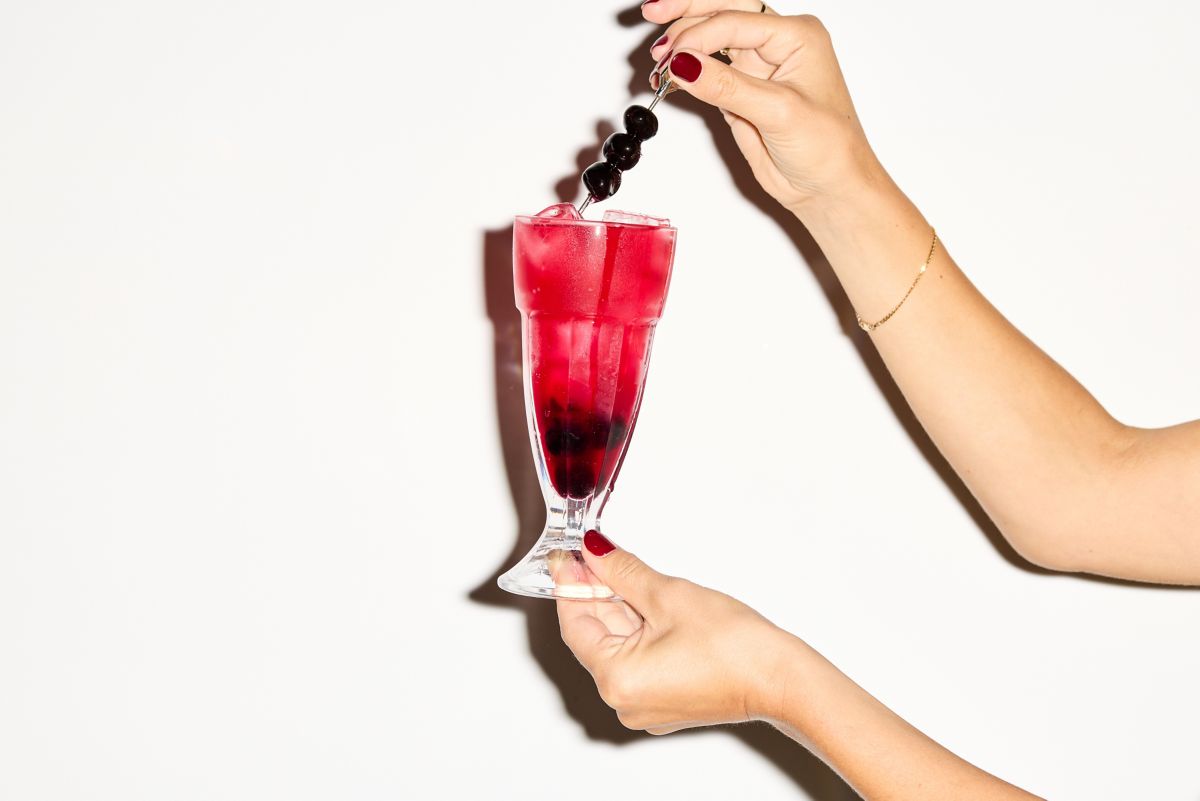 Holding a Dirty Shirley and the skewered cherries as garnish 