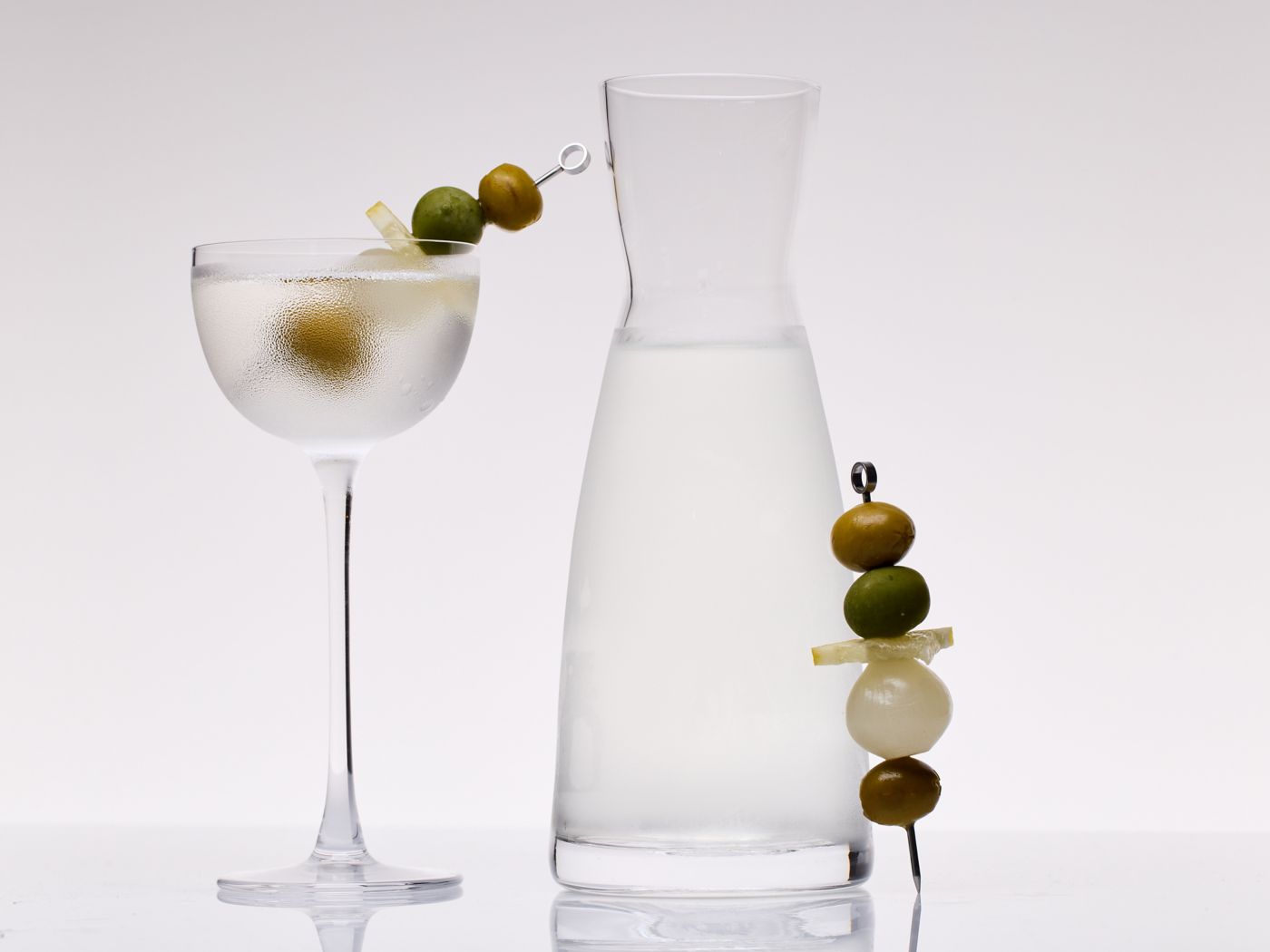 The Freezer Door Martini in a carafe and a glass with skewered olives and pickled onions
