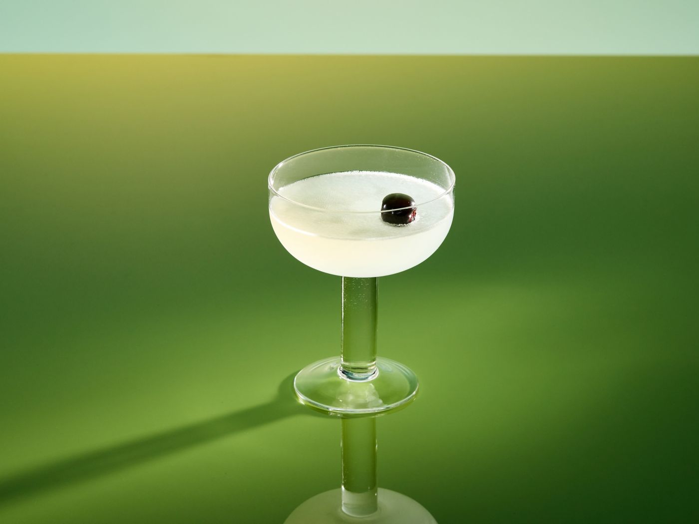 The Aviation cocktail in a coupe glass against a green background