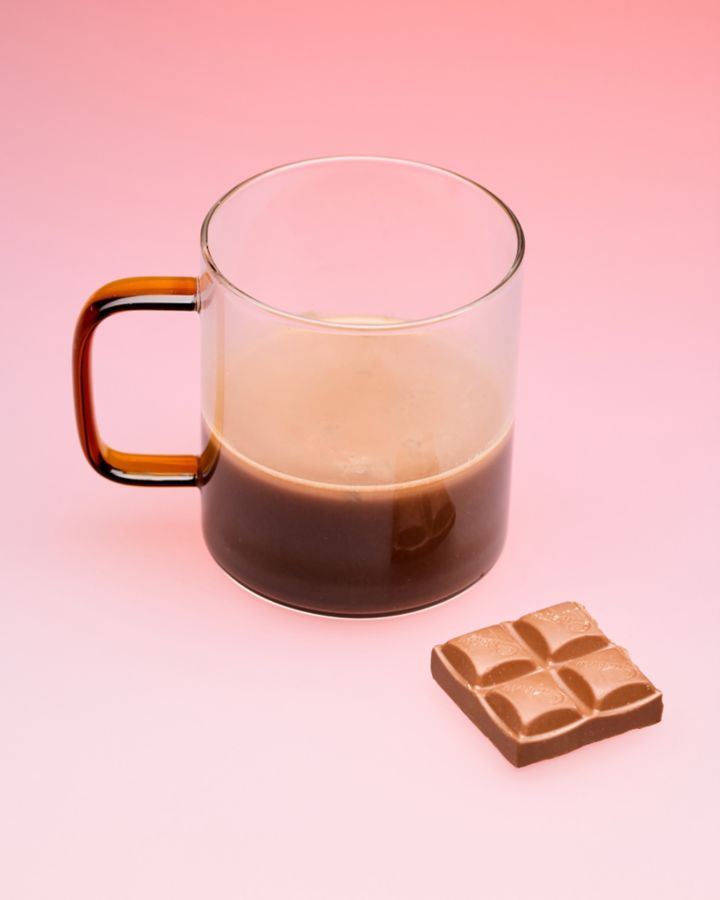 A mug of Dan's Hot Chocolate with a piece of chocolate next to it