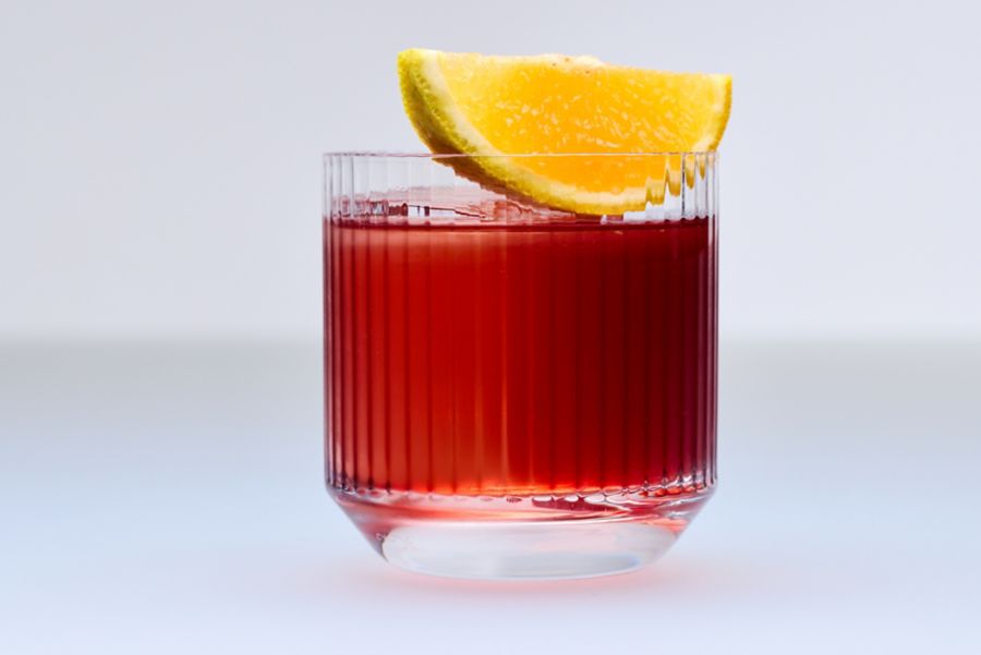 A glass of Negroni cocktail with an orange wedge garnish