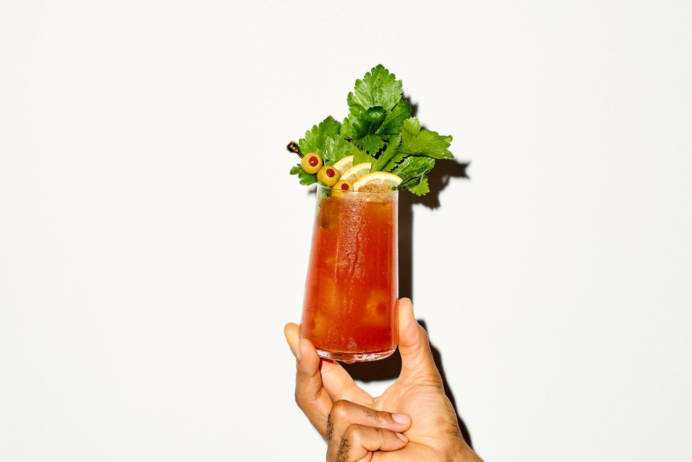 Holding a Bloody Mary cocktail against a white background