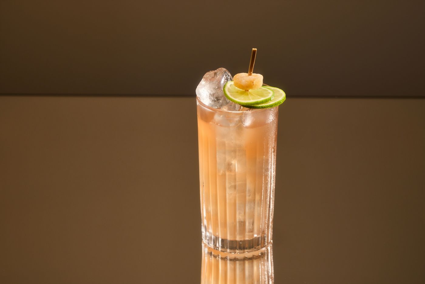 The Dark 'n' Stormy cocktail in a tall glass, garnished with lime and crystallised ginger 