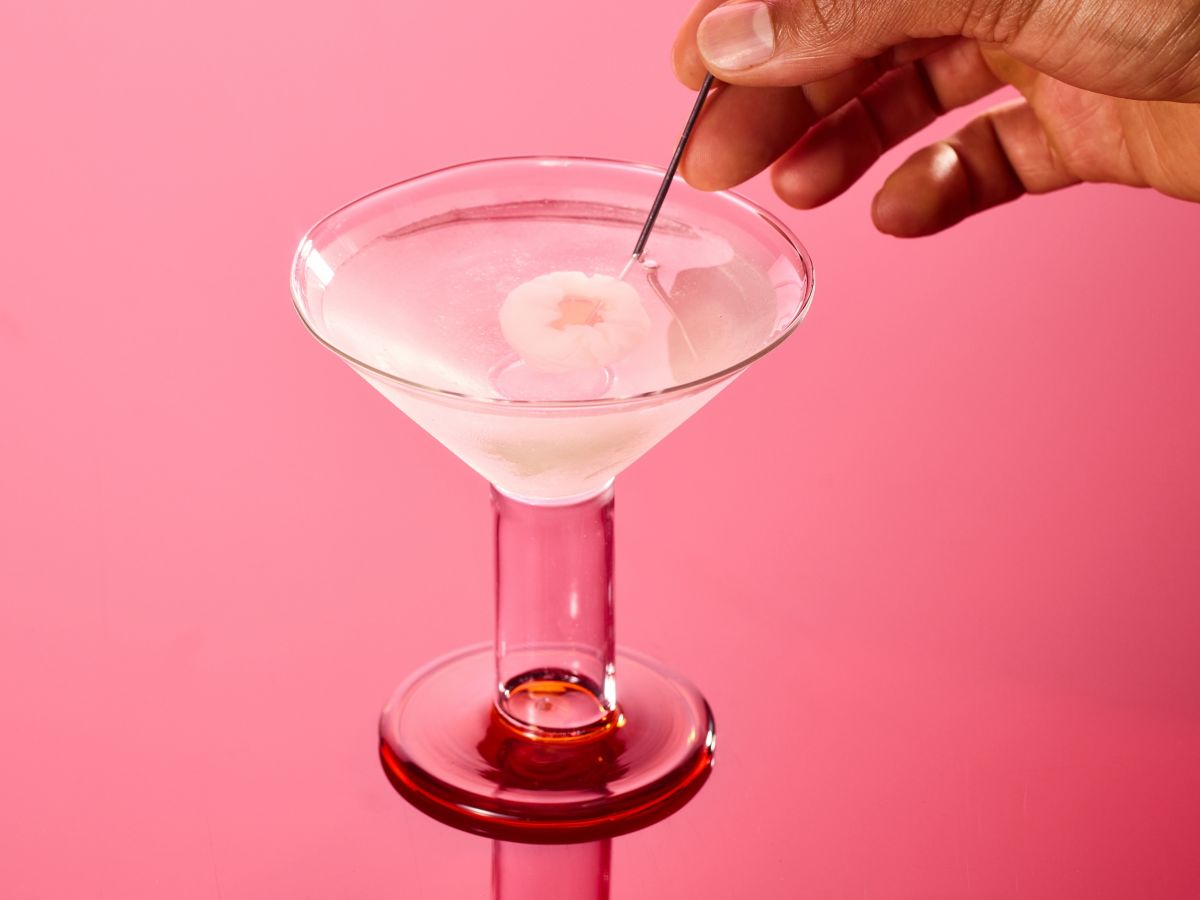 Placing a skewered lychee into a Lychee Martini 