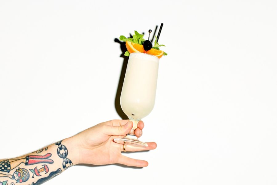 Holding a Piña Colada in a hurricane glass 