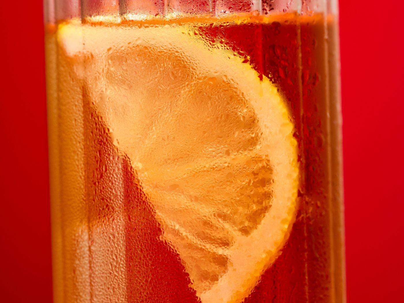 Looking into a tall glass holding a Whisky Highball with a slice of lemon 