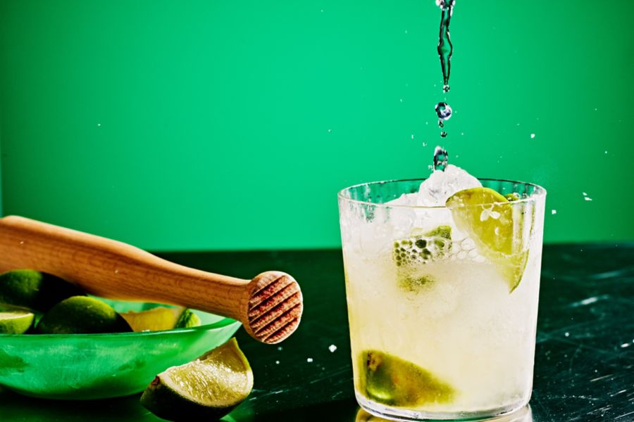 Mixing a Caipirinha with cachaça, lime, sugar and soda 