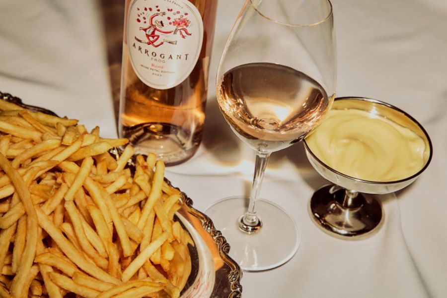 The Arrogant Frog Rosé on a table with fries and mustard