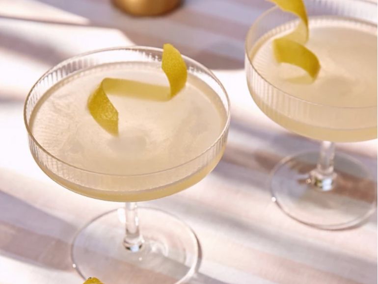 Two Bee's Knees cocktails in coupe glasses with a lemon twist
