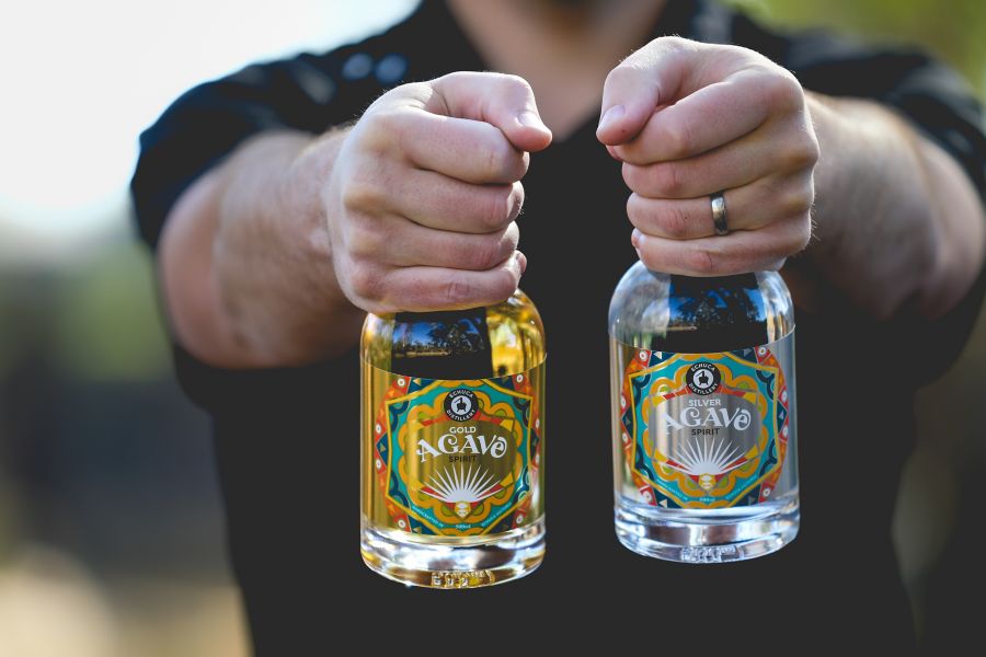 Holding two bottles of Echuca Distillery agave spirits
