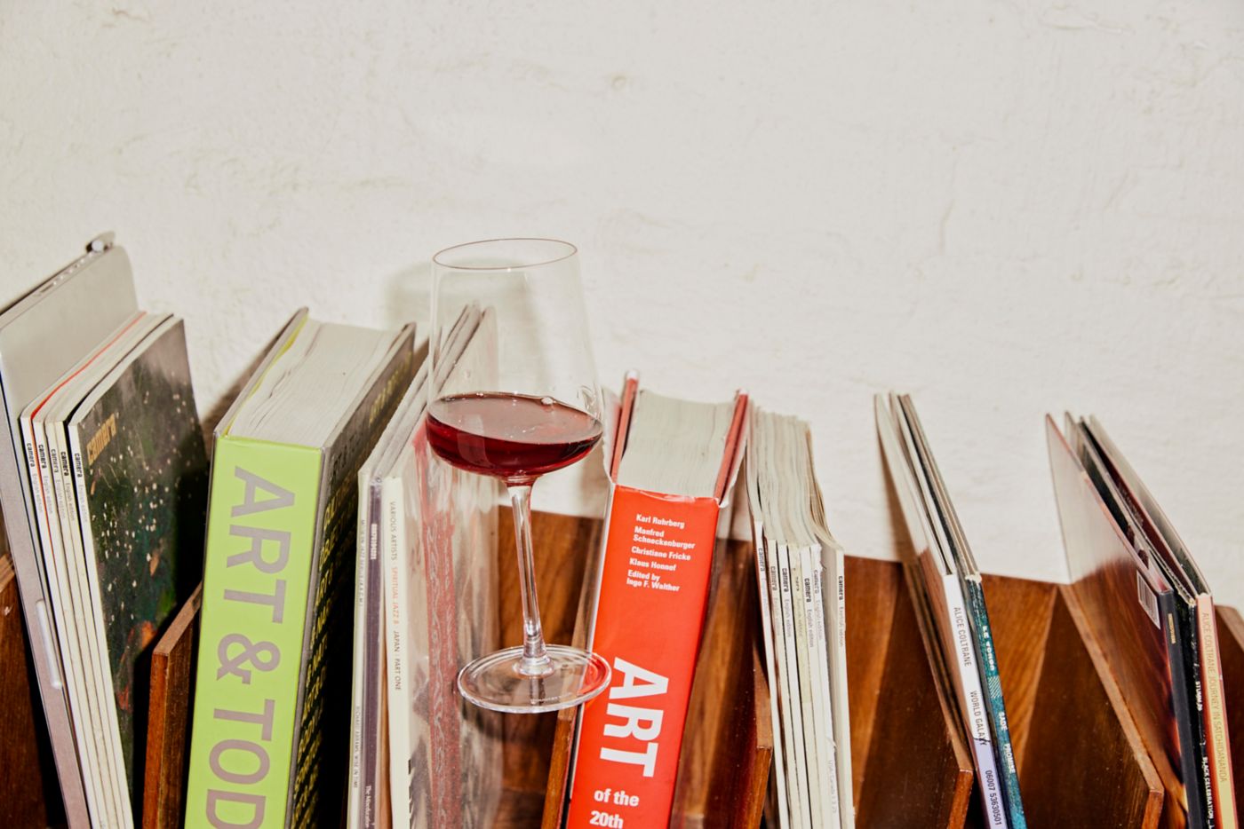 A glass of wine on a shelf of books about wine 